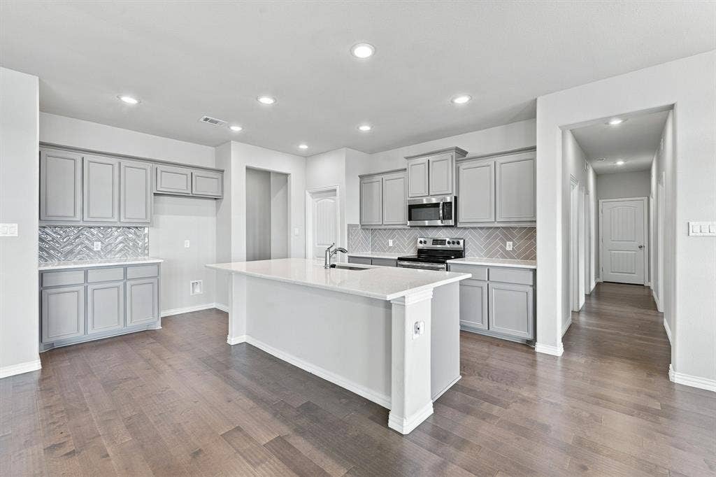 Kitchen featuring grey shaker-style cabinetry, white countertops, a herringbone-pattern backsplash, recessed lighting, and wood-finish flooring