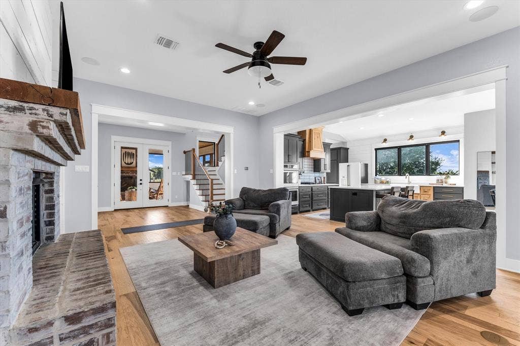23010 Rosebud Road, Burlington, TX 76519 Whitewashed brick fireplace with a natural wood mantel, light wood-finish flooring, recessed lighting, ceiling fan, and extensive millwork