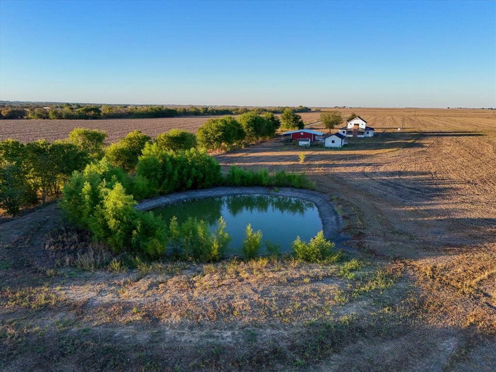 23010 Rosebud Road, Burlington, TX 76519 Expansive acreage featuring a natural pond, mature trees, open pastures, and multi-structure homestead