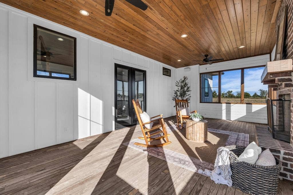 23010 Rosebud Road, Burlington, TX 76519 Covered patio featuring wood-paneled ceiling, white board-and-batten siding, recessed lighting, and a brick fireplace