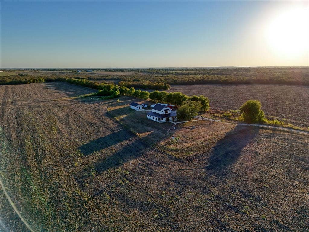 23010 Rosebud Road, Burlington, TX 76519 Aerial perspective of expansive acreage featuring a detached structure, gravel driveway, and mature trees