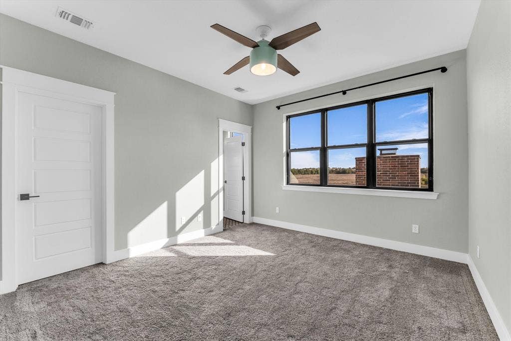 23010 Rosebud Road, Burlington, TX 76519 Neutral wall tones paired with dark-framed windows, carpeted flooring, and a modern ceiling fan with integrated lighting