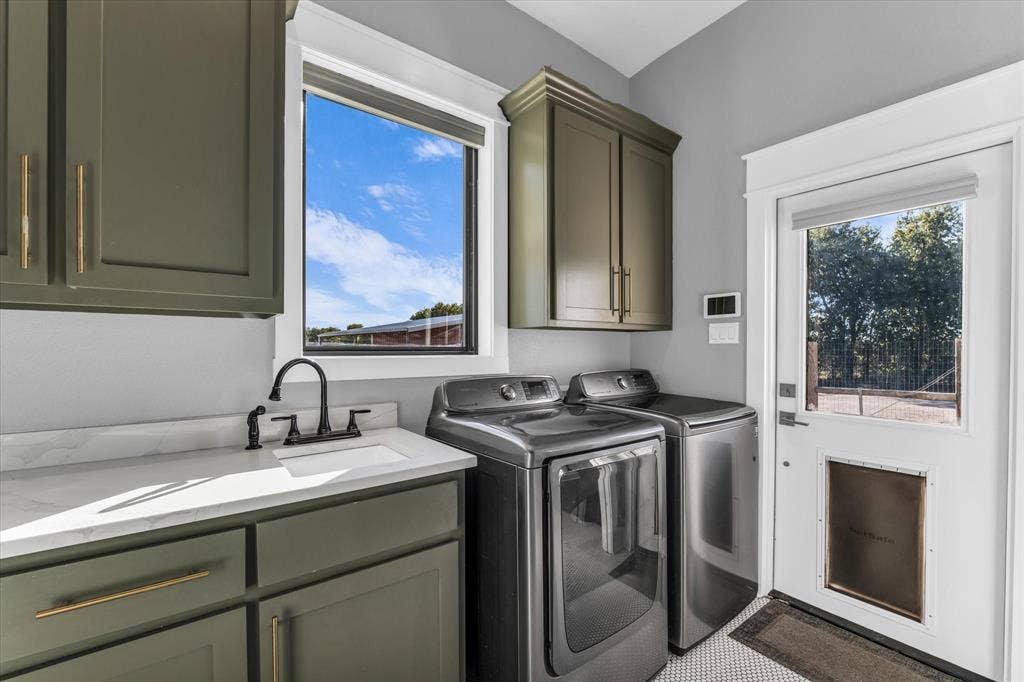 23010 Rosebud Road, Burlington, TX 76519 Laundry room featuring olive green shaker-style cabinetry, light-toned stone-finish countertops, an undermount sink with a matte black faucet, and an exterior door with an integrated pet door