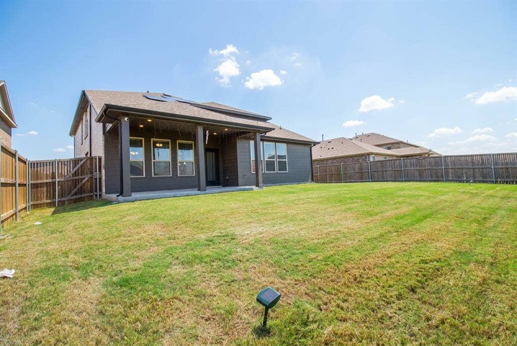 Rear exterior featuring a covered patio, brick and siding facade, and a fenced backyard