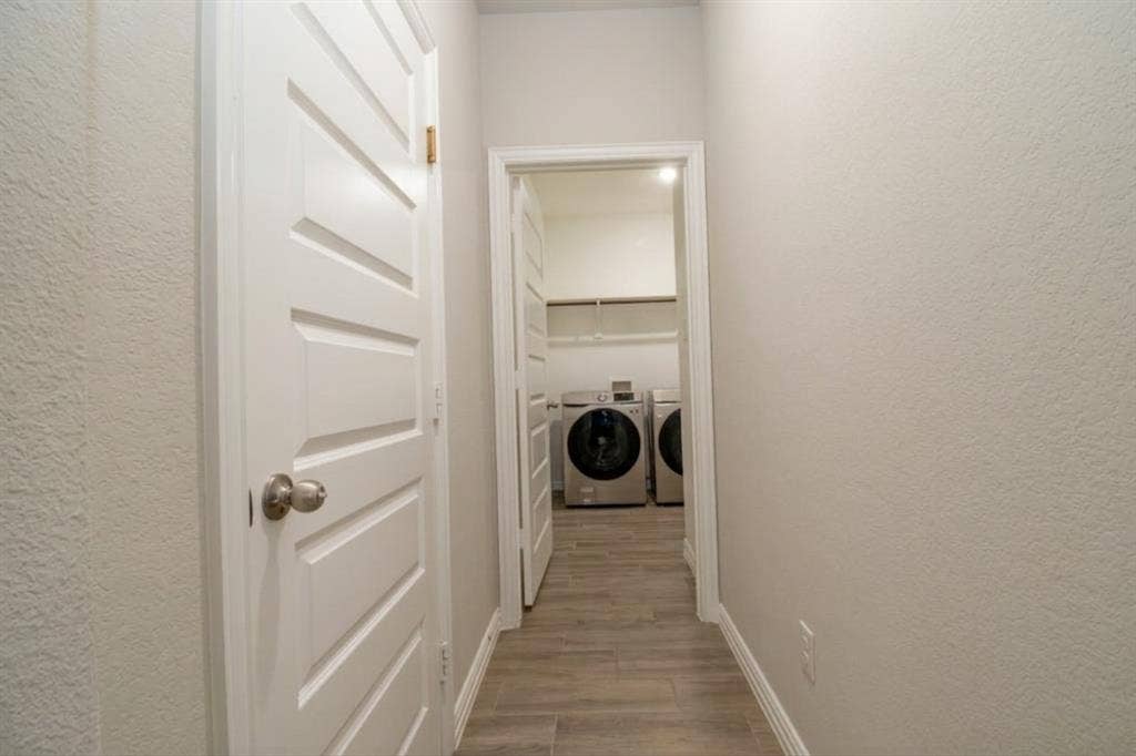 Entry from garage and Laundry space to the left featuring wood-finish tile flooring, white four-panel doors, and built-in white shelving