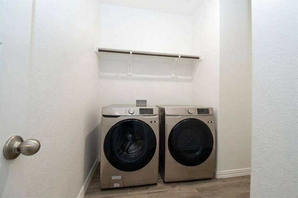 Laundry area featuring wood-finish flooring, white walls, and a built-in wall-mounted shelving unit