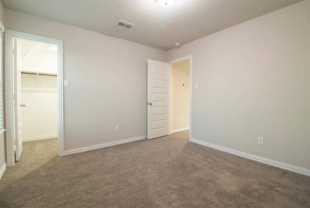 Bedroom3 Neutral-toned room featuring neutral carpeting, six-panel interior doors, and a walk-in closet with built-in shelving