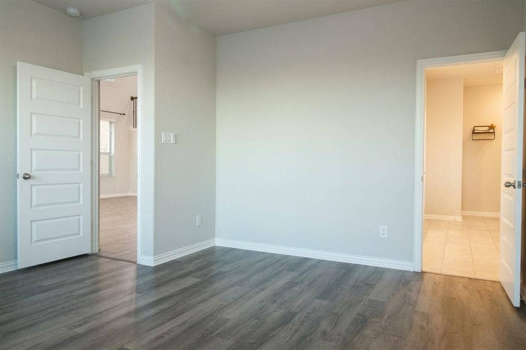 Neutral-toned interior space featuring wood-finish flooring, crisp white walls, and five-panel interior doors