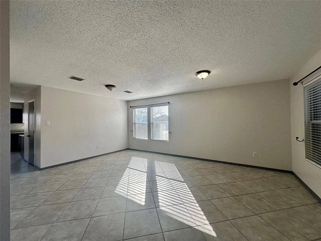 600 Claiborn Lane, Wylie, TX 75098 Open-concept room featuring neutral-toned tile flooring, dual-window configuration, and dual flush-mount ceiling light fixtures