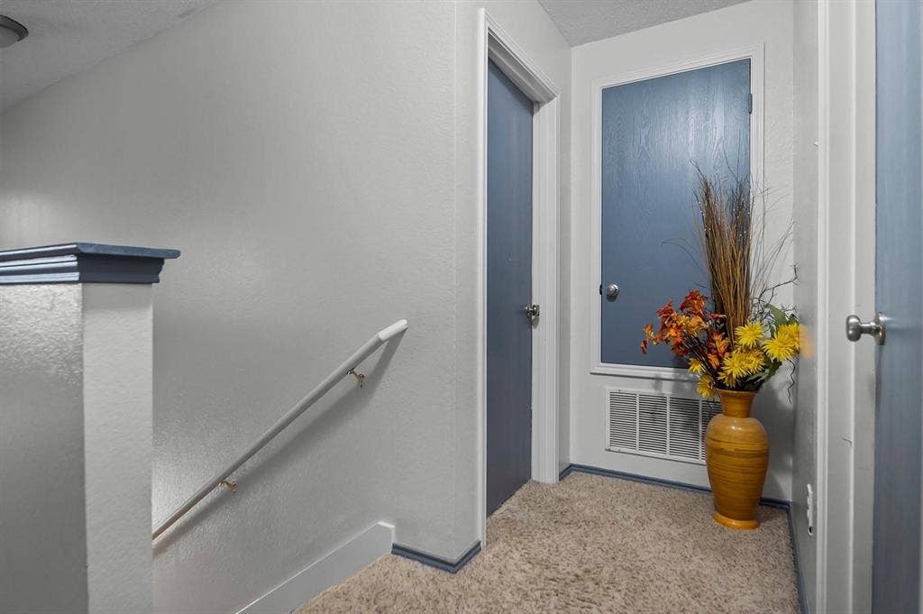 600 Claiborn Lane, Wylie, TX 75098 Interior space featuring neutral wall paint, solid-core blue interior doors, carpeted flooring, and a half-wall with a cap rail and mounted handrail