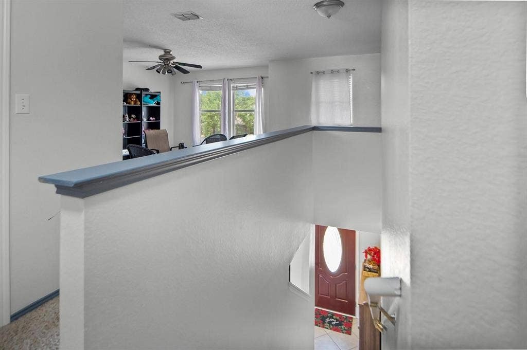 600 Claiborn Lane, Wylie, TX 75098 Interior landing with a painted wood cap railing, ceiling fan, and entry door featuring an oval glass insert