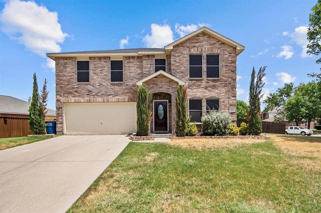600 Claiborn Lane, Wylie, TX 75098 Two-story exterior featuring multi-tonal masonry, a dual-car garage, and an arched entry with an oval-glass front door
