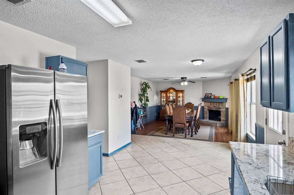 600 Claiborn Lane, Wylie, TX 75098 Kitchen featuring blue-toned cabinetry, light stone-finish countertops, and stainless steel refrigerator