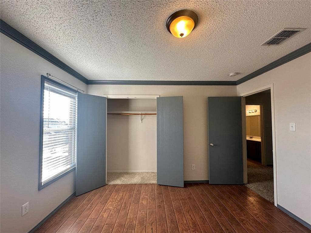 600 Claiborn Lane, Wylie, TX 75098 Interior space featuring wood-finish flooring, two-tone crown molding, built-in closet with shelving, flush-mount ceiling lighting, and a single-pane window