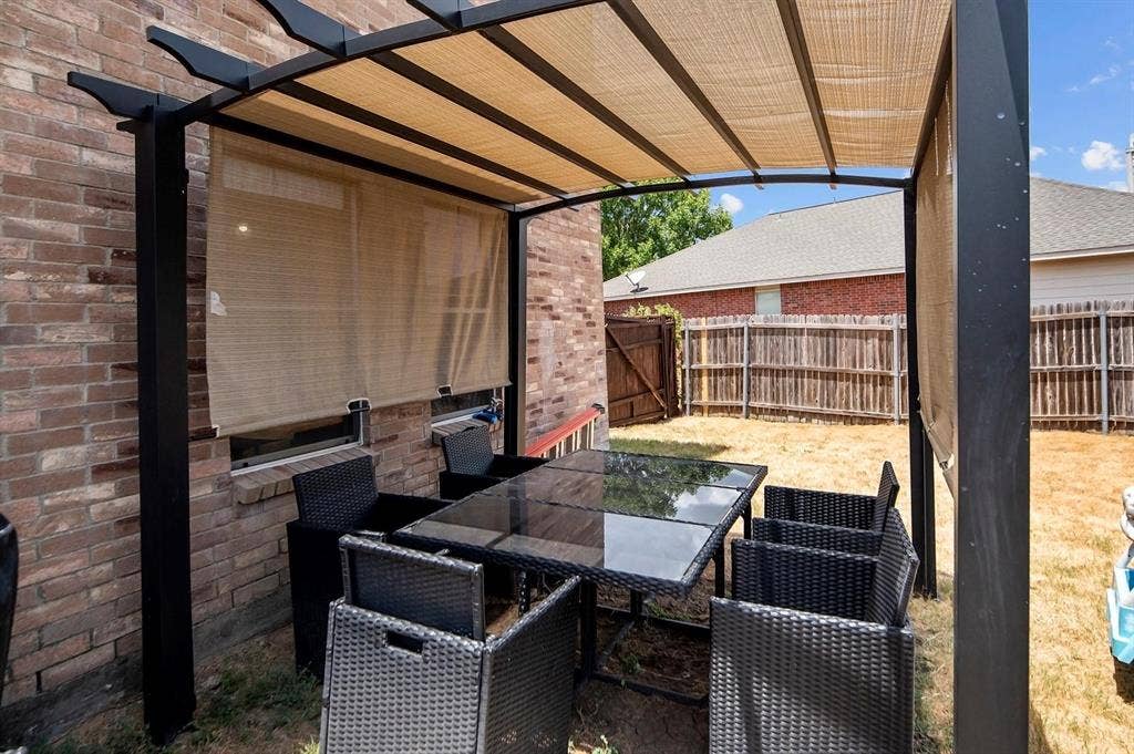 600 Claiborn Lane, Wylie, TX 75098 Outdoor living space featuring a black metal pergola with a retractable shade canopy and a brick exterior wall