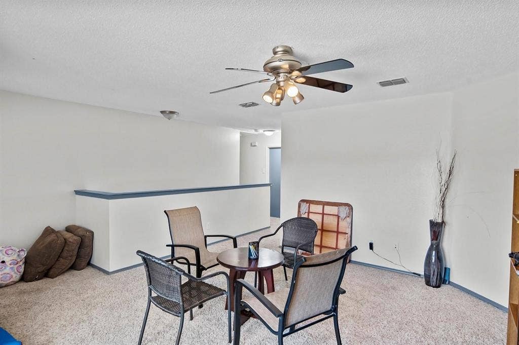 600 Claiborn Lane, Wylie, TX 75098 Neutral interior space featuring carpeted flooring, a ceiling fan with integrated lighting, and a half-wall partition with a contrasting trim finish