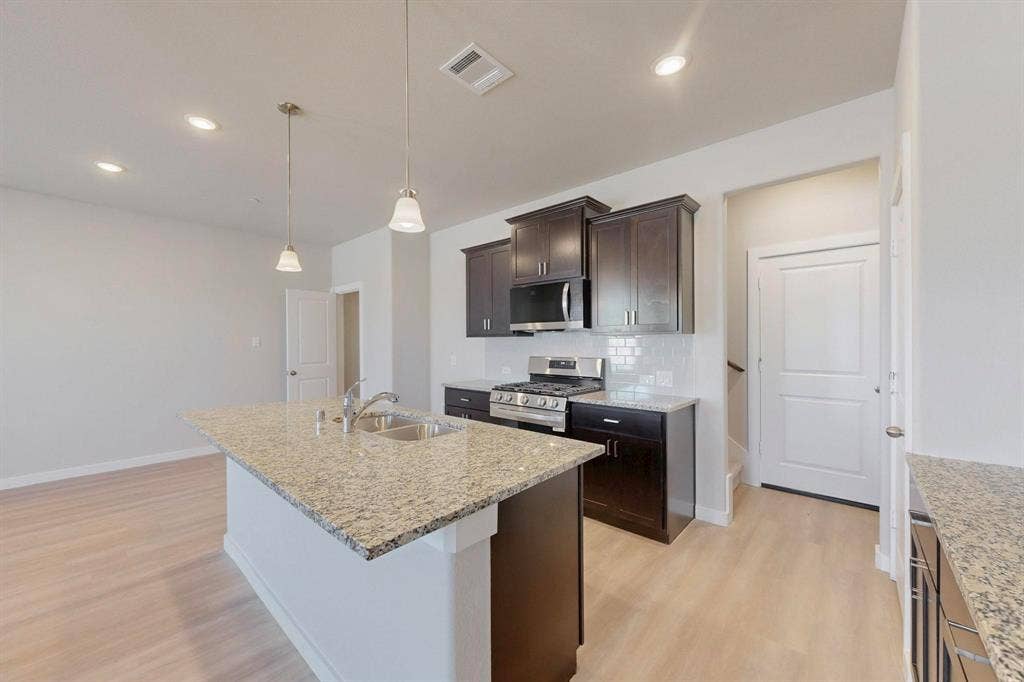 1424 Starlight Trail, Mesquite, TX 75181 Kitchen featuring stainless steel appliances, dark brown cabinets, tasteful backsplash, light wood-style flooring, and hanging light fixtures