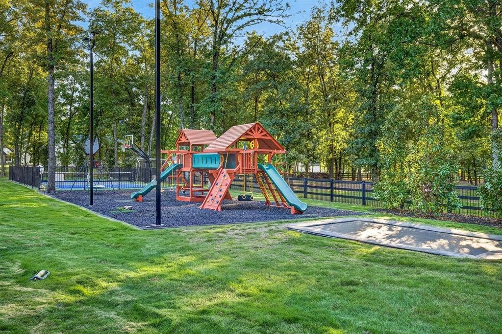 104 Oakbend Trail, Mabank, TX 75147 Expansive backyard featuring a playground, trampoline, and basketball court surrounded by mature trees.