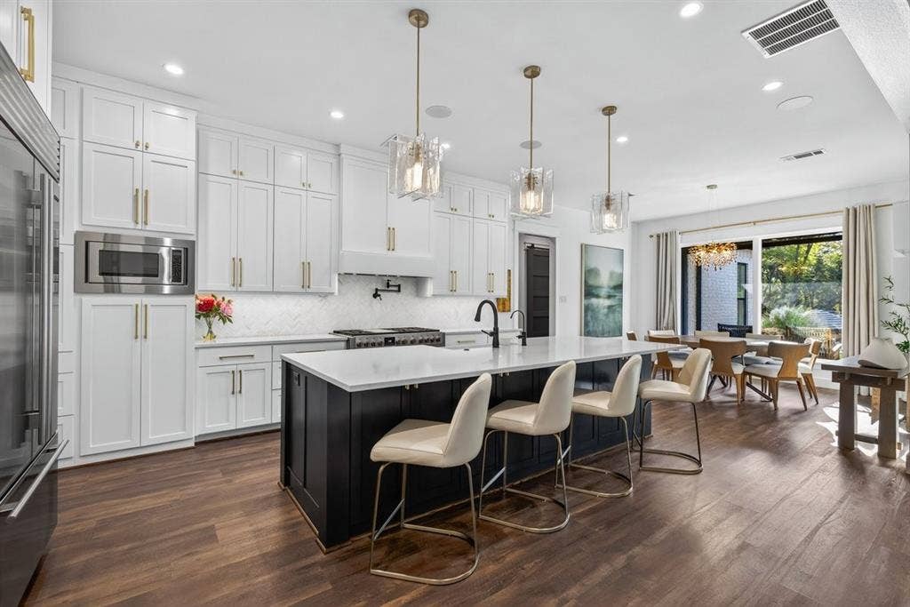 104 Oakbend Trail, Mabank, TX 75147 Bar seating with island storage, gas range, and elegant pendant lighting, opening to the dining area.