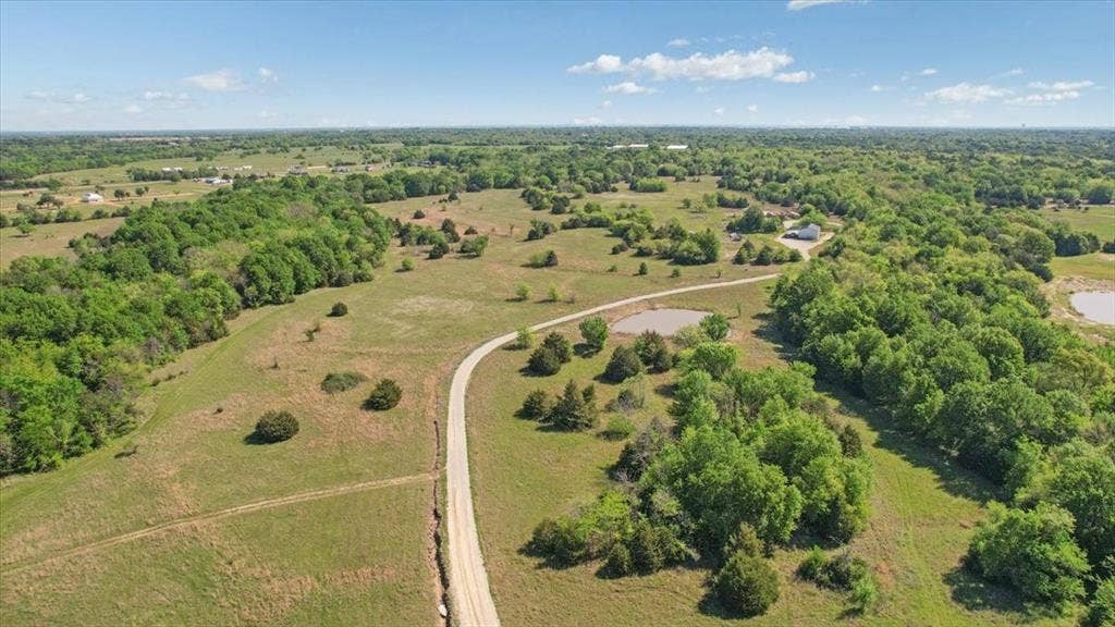 2377 FM 36 N, Farmersville, TX 75442 Expansive acreage featuring rolling terrain, clusters of mature hardwood trees, natural ponds, and a winding gravel road