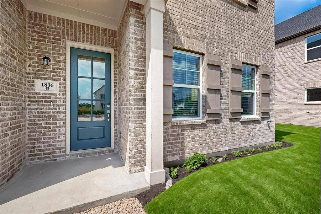 1432 Starlight Trail, Mesquite, TX 75181 View of exterior entry with brick siding, a porch, and a yard