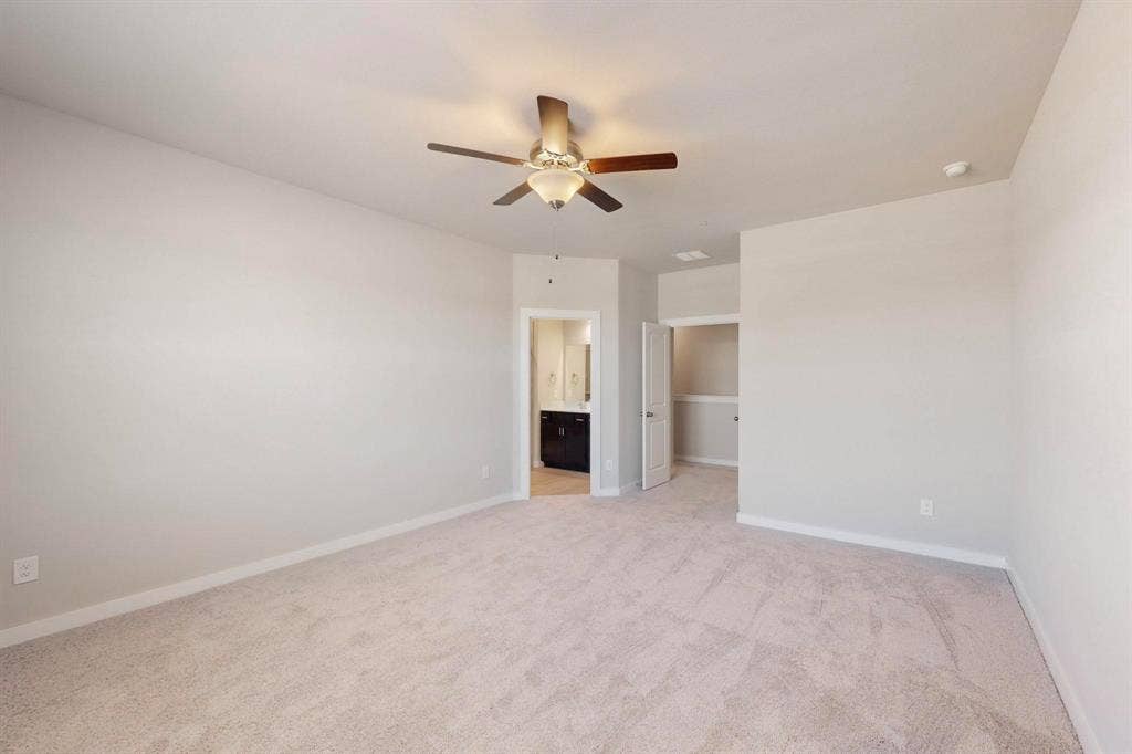 1432 Starlight Trail, Mesquite, TX 75181 Unfurnished bedroom featuring a spacious closet, light carpet, a ceiling fan, and ensuite bath