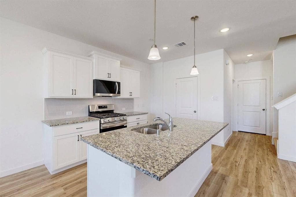 1504 Starlight Trail, Mesquite, TX 75181 Kitchen featuring appliances with stainless steel finishes, white cabinetry, light stone countertops, light wood-style floors, and recessed lighting