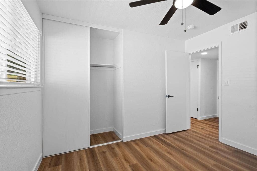 2621 Amherst Court, Irving, TX 75038 Room featuring wood-finish flooring, sliding door closet with built-in shelving, ceiling fan with integrated lighting, and horizontal blinds