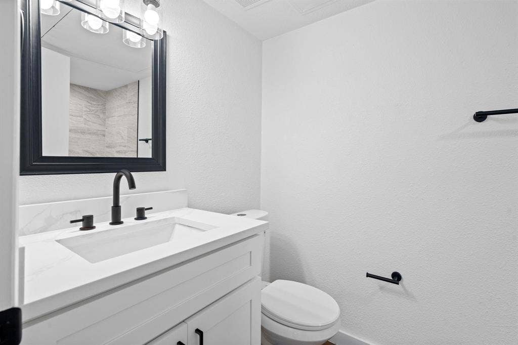 2621 Amherst Court, Irving, TX 75038 White vanity featuring a white countertop with an integrated rectangular sink, matte black widespread faucet, black-framed mirror, and matching matte black hardware