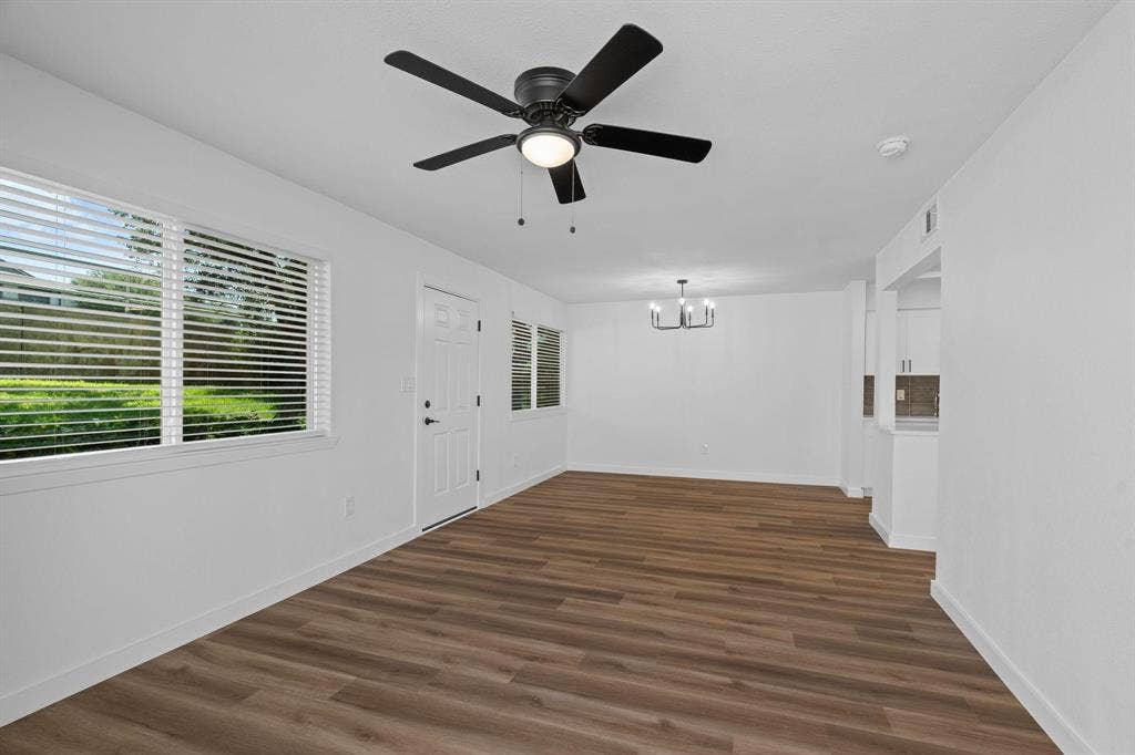 2621 Amherst Court, Irving, TX 75038 Wood-finish flooring, matte black ceiling fan with integrated lighting, multipane windows with horizontal blinds, and a modern six-light chandelier