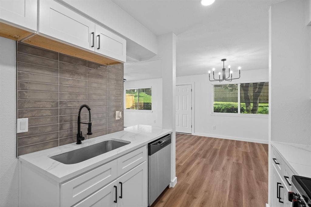 2621 Amherst Court, Irving, TX 75038 Kitchen featuring white shaker-style cabinetry, quartz countertops, a grey tile backsplash, stainless steel undermount sink with a matte black pulldown faucet, and wood-finish flooring