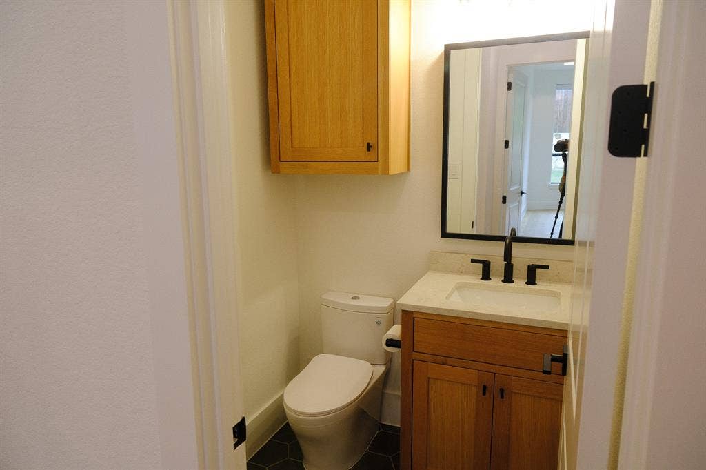 10694 Hollydale Lane, Frisco, TX 75035 Vanity featuring wood cabinetry, a light-toned countertop with an integrated sink, and matte black fixtures
