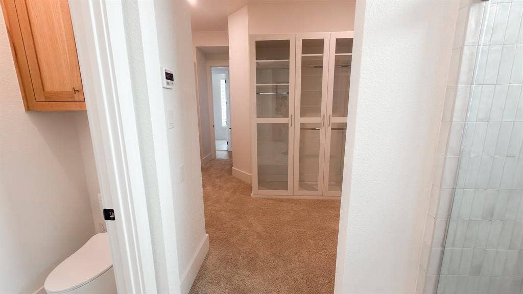 10694 Hollydale Lane, Frisco, TX 75035 Built-in storage cabinetry with glass-paneled doors, wall-mounted upper cabinetry, carpeted flooring, and tiled shower surround