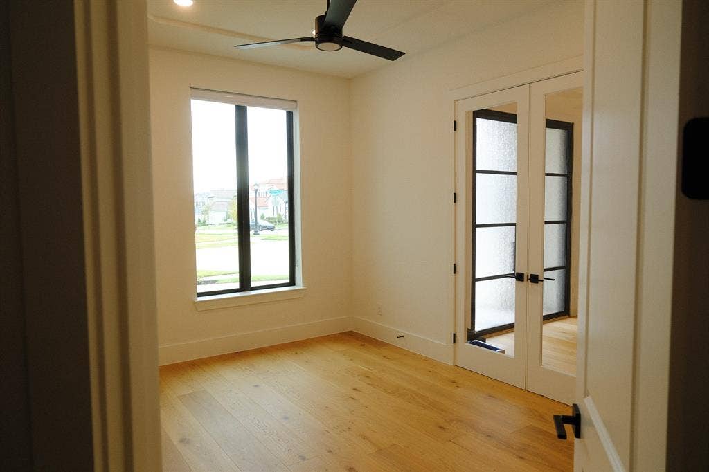 10694 Hollydale Lane, Frisco, TX 75035 Study Room featuring wood-finish flooring, a matte black ceiling fan, a vertical window with black trim, and French doors with mullioned glass panes