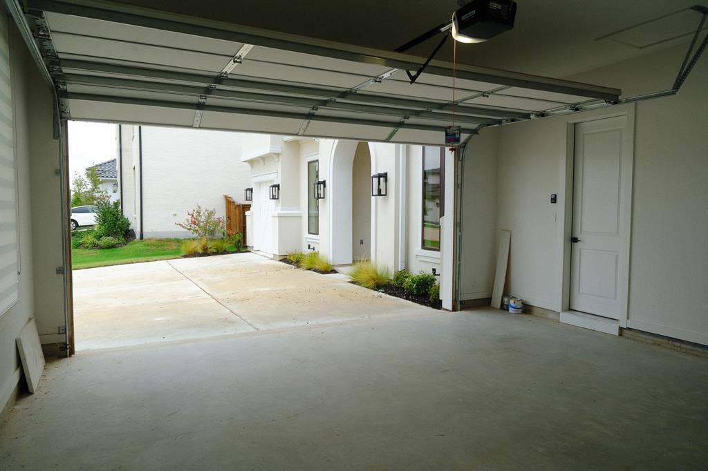 10694 Hollydale Lane, Frisco, TX 75035 Attached two-car garage featuring a motorized sectional door, concrete flooring, and interior entry door