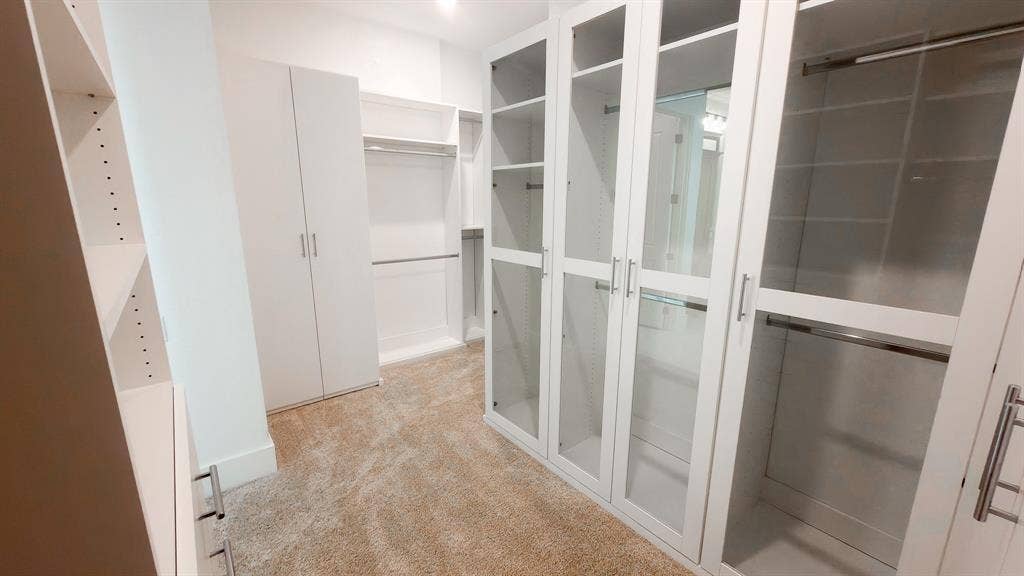 10694 Hollydale Lane, Frisco, TX 75035 Custom built-in storage system featuring floor-to-ceiling cabinetry, glass-paneled cabinet doors, metal hardware, and adjustable shelving units