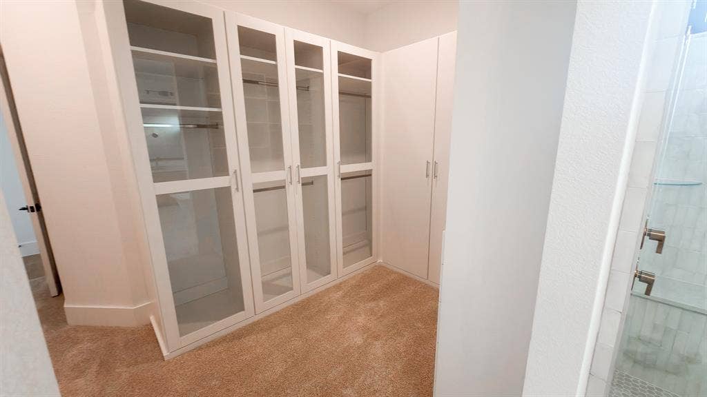 10694 Hollydale Lane, Frisco, TX 75035 Built-in white cabinetry featuring glass-front doors, integrated shelving, and hanging rods