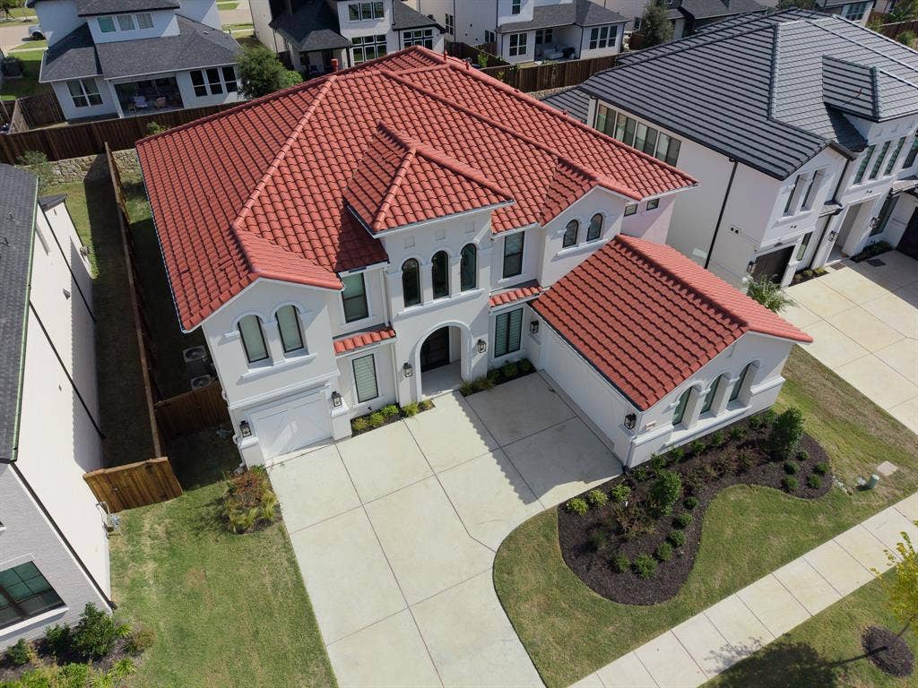10694 Hollydale Lane, Frisco, TX 75035 Two-story exterior featuring a red tile roof, arched windows, concrete driveway, and manicured front lawn landscaping