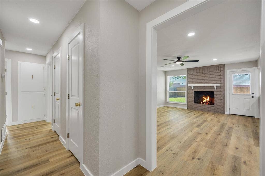 Wood-finish flooring, recessed lighting, brick-accented fireplace, and built-in cabinetry