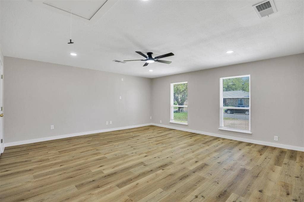 Spacious room featuring wood-finish flooring, neutral wall paint, recessed lighting, and a ceiling fan with integrated lighting