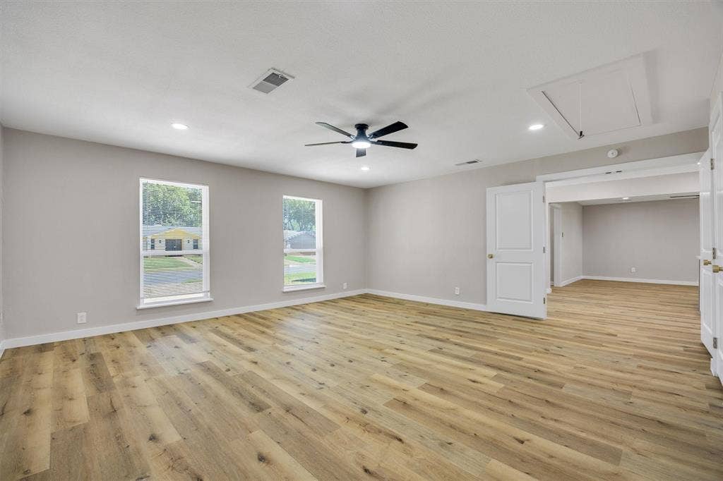Neutral-toned interior featuring wood-finish flooring, recessed lighting, a modern ceiling fan, and double windows