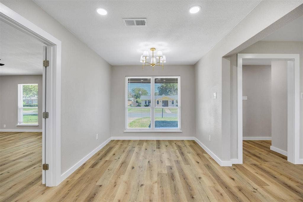 Neutral wall palette featuring wood-finish flooring, recessed lighting, multi-arm chandelier, and double-pane windows