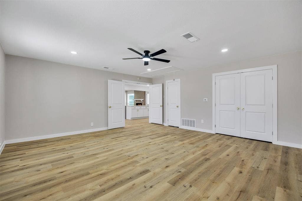 Spacious room featuring wood-finish flooring, recessed lighting, a ceiling fan, and double-panel doors