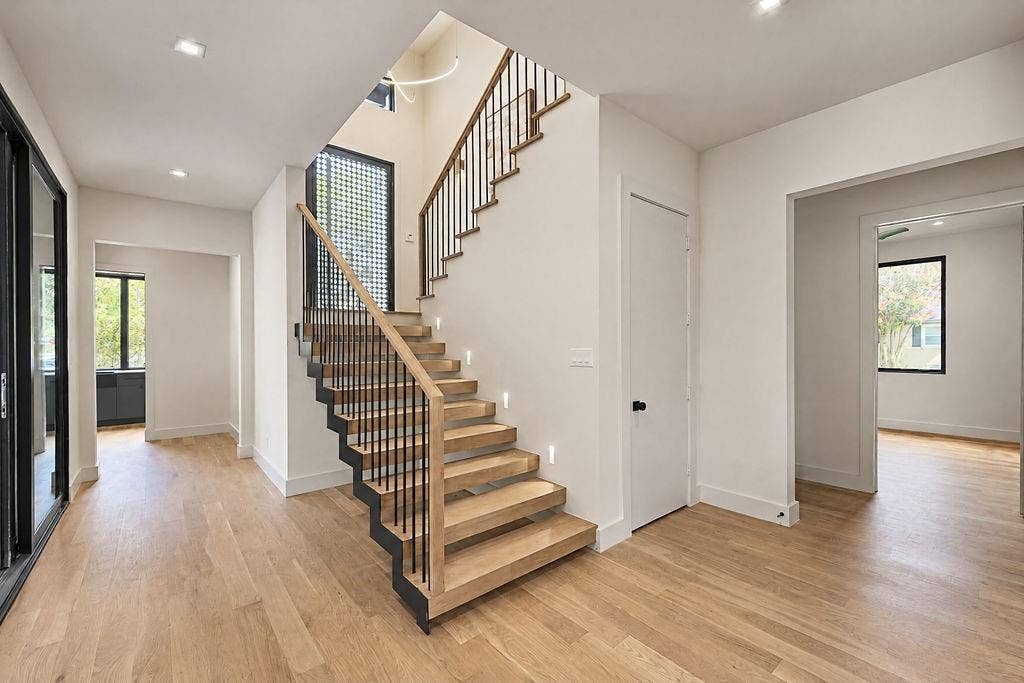 Step inside to a light-filled entry where rich hardwood floors and an open-riser floating staircase set an inviting, airy mood from the moment you cross the threshold