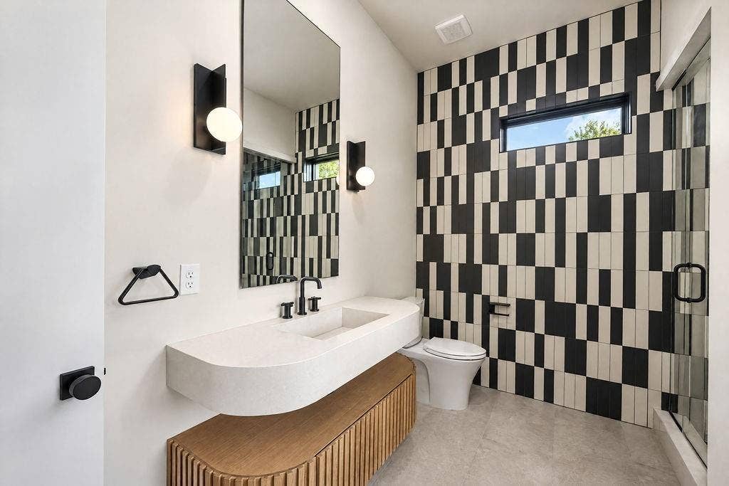 Experience bold modern personality with graphic black-and-white tile, a sculptural sink, and sleek black fixtures