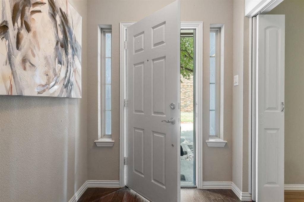 Entryway featuring a six-panel exterior door, dual sidelights, wood-finish flooring, and a multi-panel bifold door