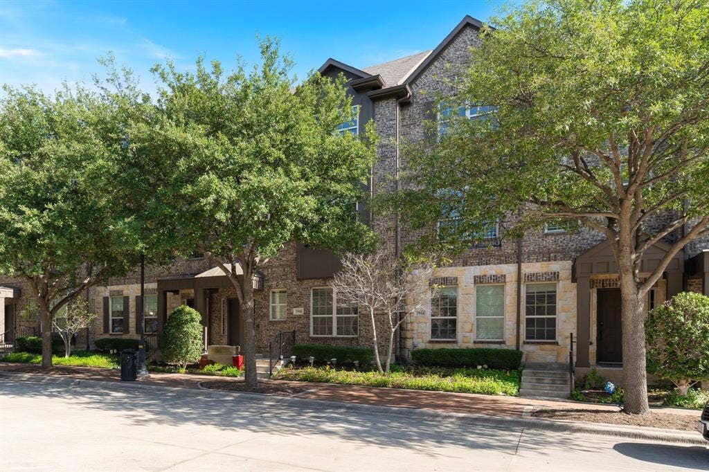 Multi-story exterior featuring multi-toned brick and stone veneer, gabled rooflines, dark-toned trim, and covered entryways