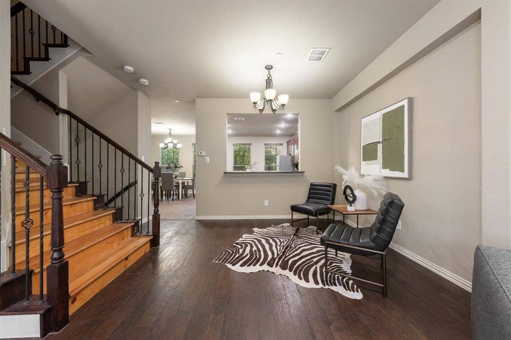 Staircase featuring wood-finish treads and wrought iron railing, dark wood-finish flooring, and pass-through window with serving counter
