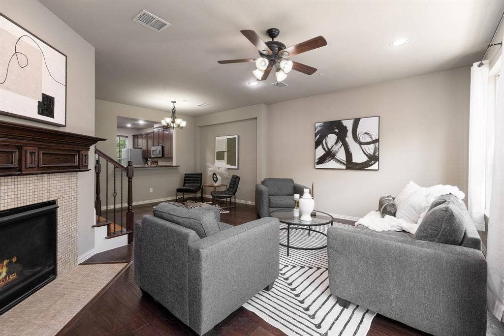 Fireplace with a decorative wood mantel, tiled surround, wood-finish flooring, recessed lighting, and a multi-blade ceiling fan with integrated lighting