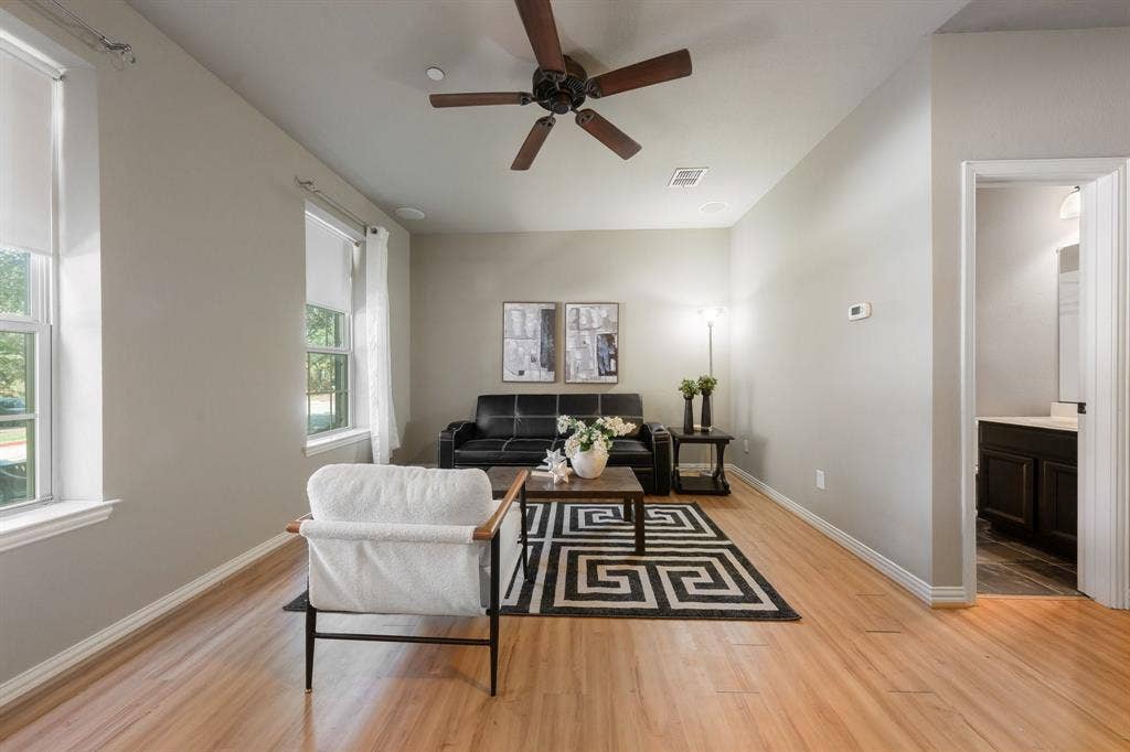 Interior room featuring high ceilings, wood-finish flooring, dual vertical windows, and a ceiling fan